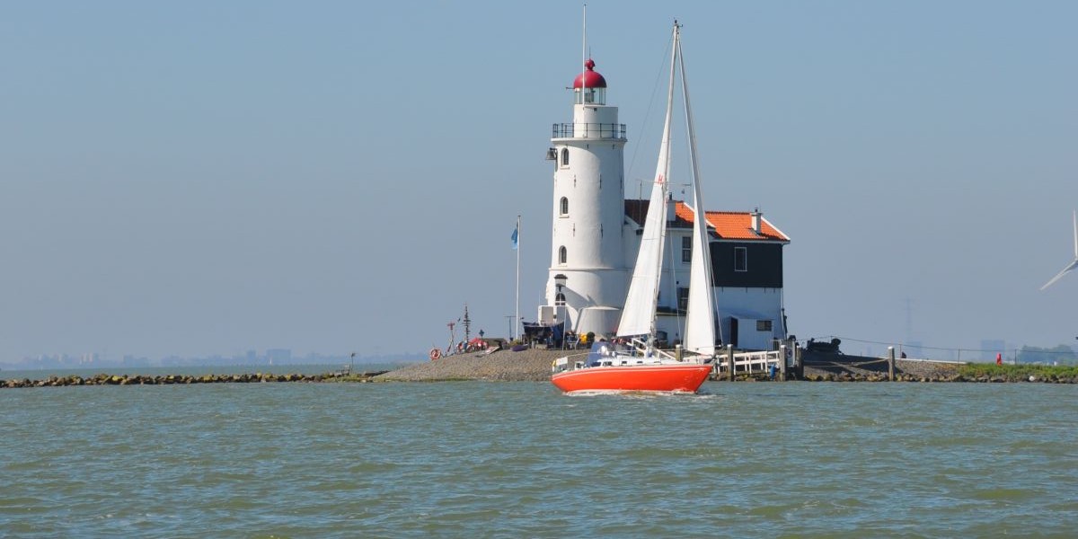 Zeilboot op het water bij een vuurtoren; welke bootverzekering past bij jouw boot? 