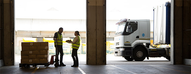 Twee mensen praten bij in loods bij vrachtwagen