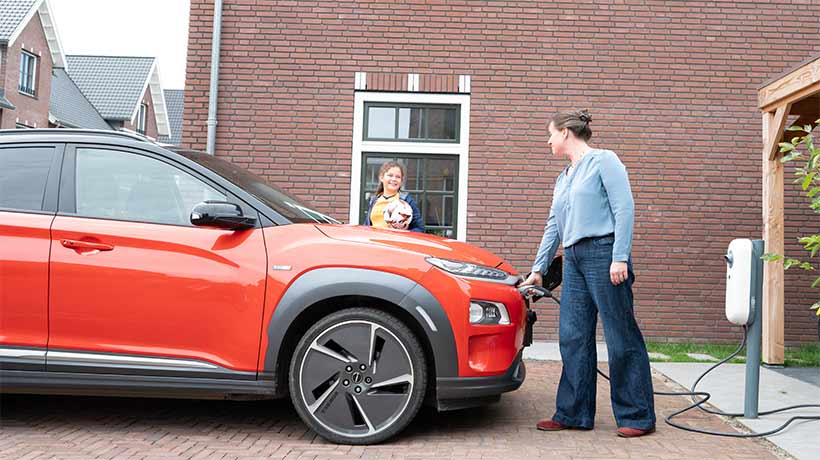 Vrouw met dochter laadt elektrische auto op