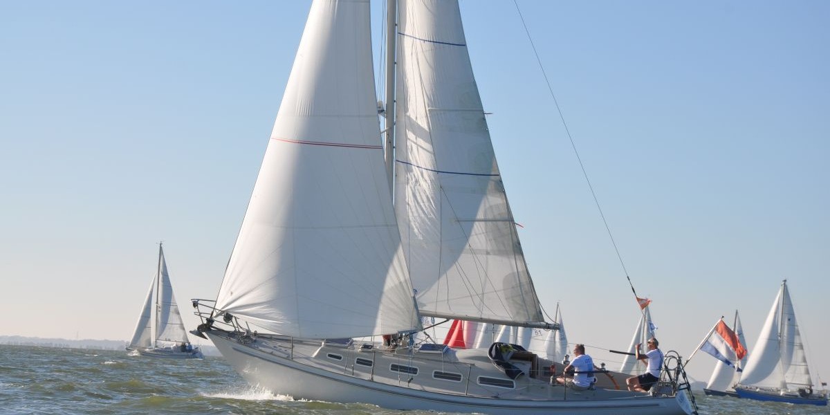 Meerdere zeilboten op het water met grote witte zeilen en een blauwe lucht
