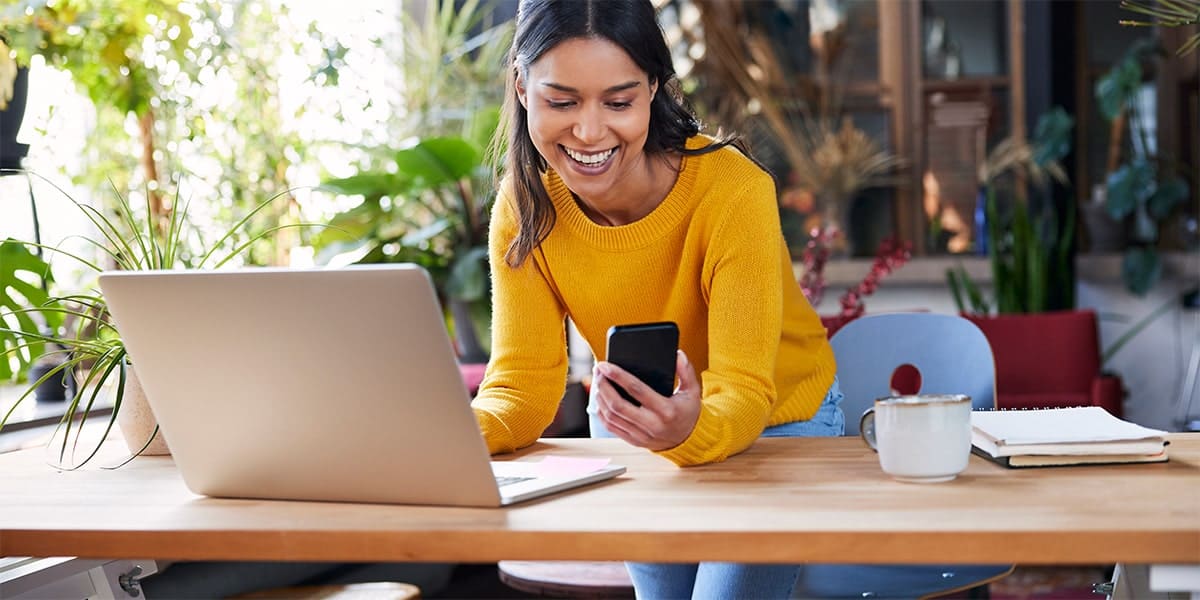Lachende vrouw met laptop en smartphone 