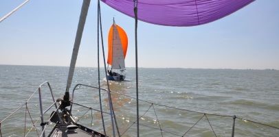 Een zeilboot op zee met een paarse en oranje zeil