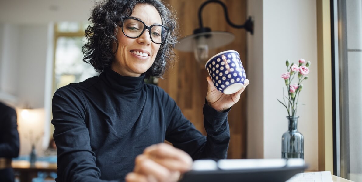 vrouw met koffie in haar hand op de tablet